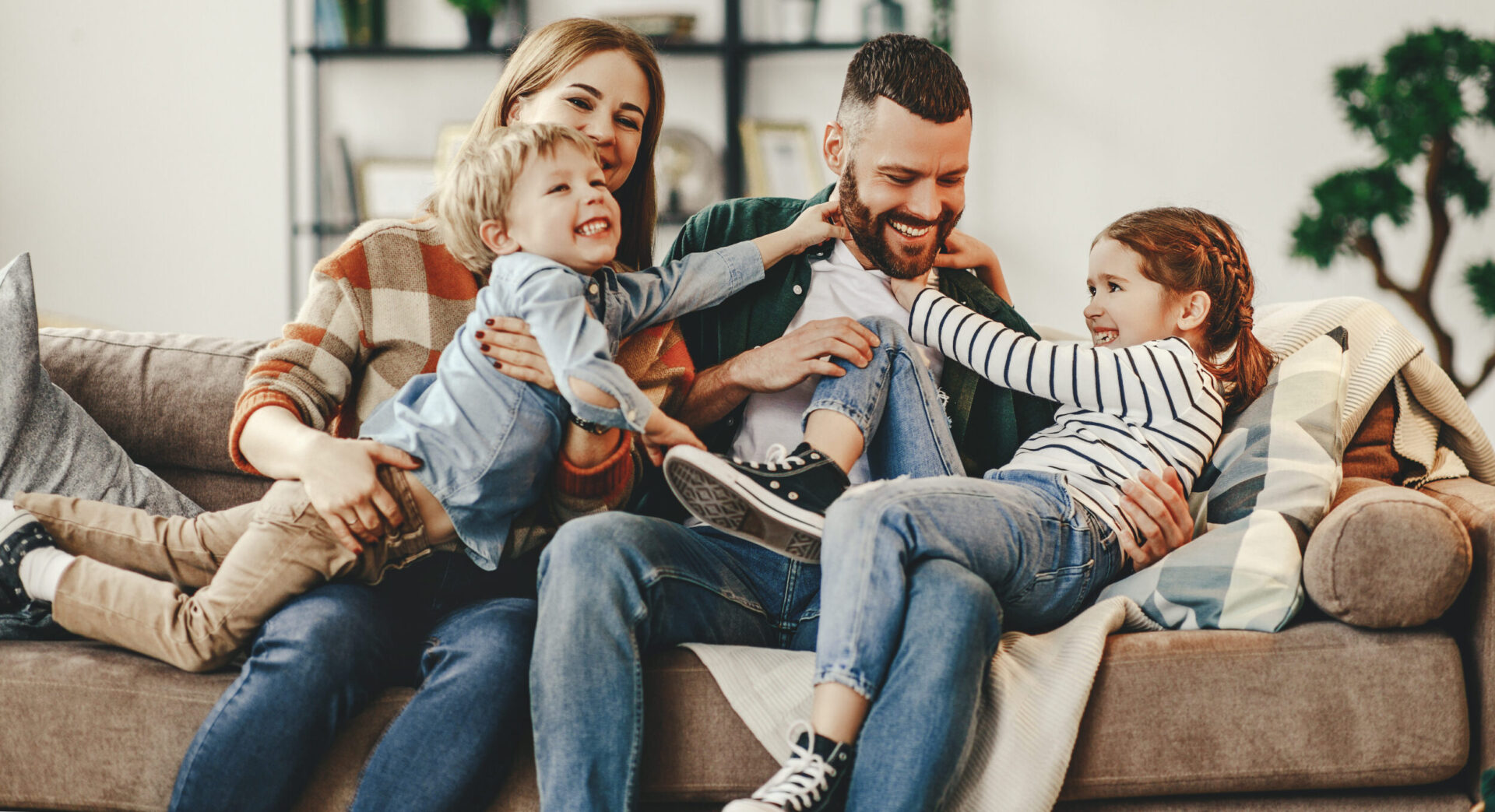 happy family mother father and kids at home on the couch